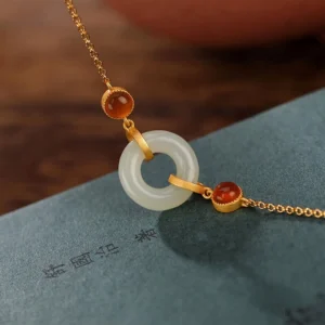 Close-up detail of gold-plated peace buckle jade bead with red agate decorative beads on dark fabric