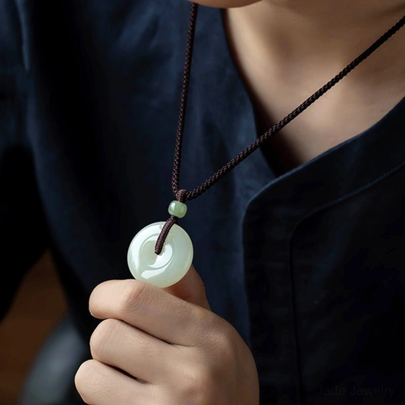 Jade peace buckle pendant necklace worn at chest level with hand holding pendant showing traditional circular design