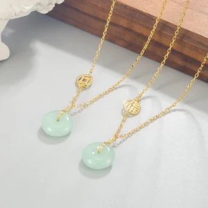 Layered jade peace buckle necklaces featuring dual gold chains, two jade pendants with fu coin charms, styled on wooden block background