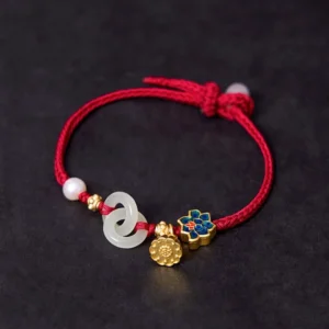 Hetian jade lotus peace buckle bracelet with red woven rope gold lotus pendant and enamel charm overhead view