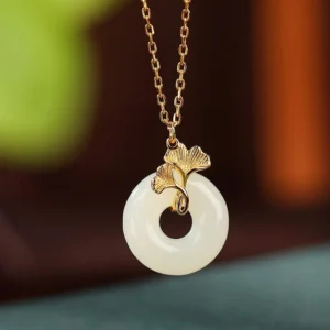 Front close-up view of natural white jade peace buckle necklace with elegant gold ginkgo ornament and fine sterling silver chain