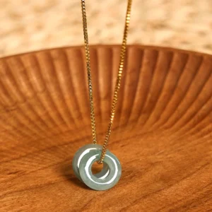 Natural jade double peace buckle pendant necklace with gold box chain on wooden surface, flat lay overhead view