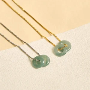 Pair of double jade peace buckle necklaces with gold and silver chain options, overhead flat lay composition
