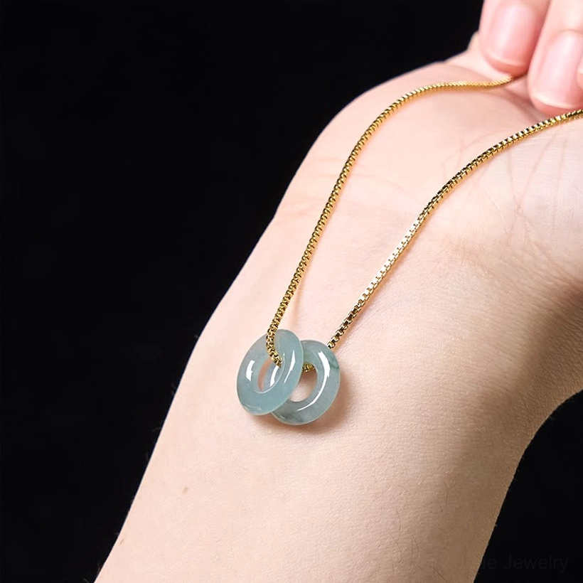 Double jade peace buckle necklace worn on back of hand, showing glossy polished jade detail