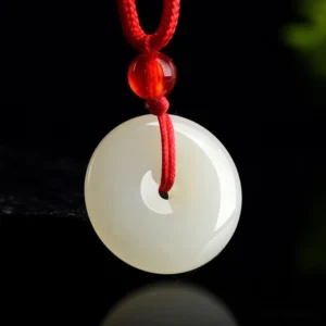 Overhead view of jade peace buckle pendant with handwoven red rope and red accent bead