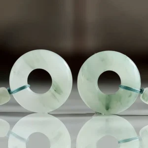 Pair of natural jade peace buckles with green veined jade and blue fastening lanyards, overhead view