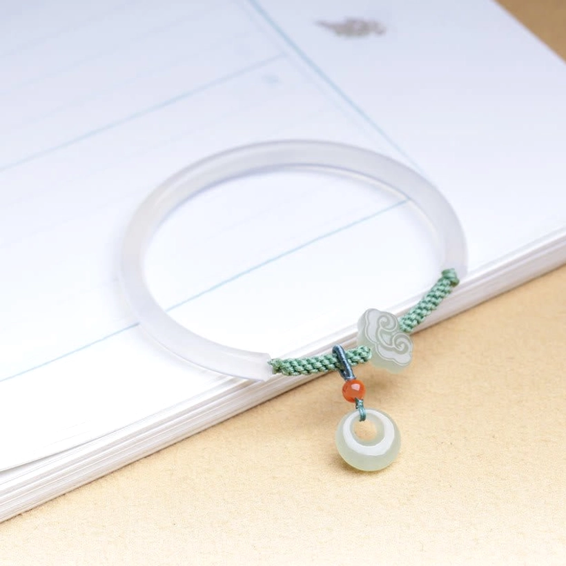 Hetian jade bracelet top-down on stacked notebooks, clear view of hanging peace buckle pendant and agate band