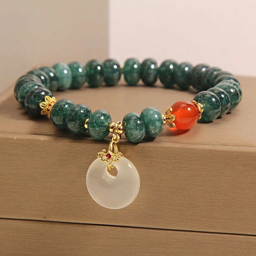 Close-up front view of jade peace buckle charm bracelet, featuring detailed white jade pendant with gold hardware and red gemstone accent