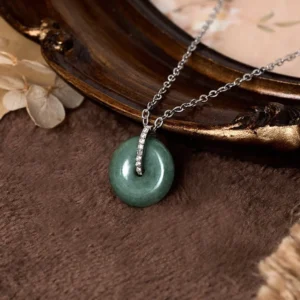 Close-up detail of jade peace buckle pendant with zircon-inlaid silver bale and smooth matte green jade stone