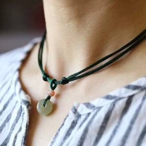 Natural jade peace buckle pendant worn on neck with dark green cord, daily wear close-up