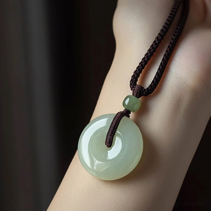 Close-up of polished natural jade peace buckle worn on forearm showing smooth glossy surface and braided cord detail