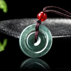 Dark green polished jade double peace buckle pendant three-quarter angle showing concentric circle design with brown braided rope and red accent bead