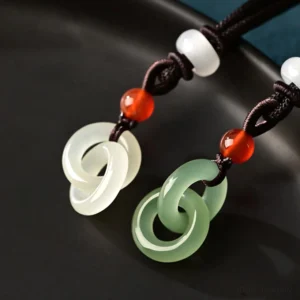 Top-down view of cyan jade and white jade double peace buckle pendants showing polished finish and interlocking circular design