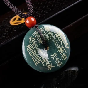 Engraved jade peace buckle necklace shown from side angle, featuring deep green jade with gold inscriptions, eight trigrams symbol, and braided cord detail