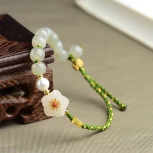 Sterling silver and jade bracelet detail view showing red flower center and gold metal accents on dark wood