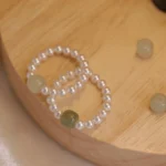 Jade and pearl beaded elastic rings flat lay on wooden surface showcasing natural jade bead colors