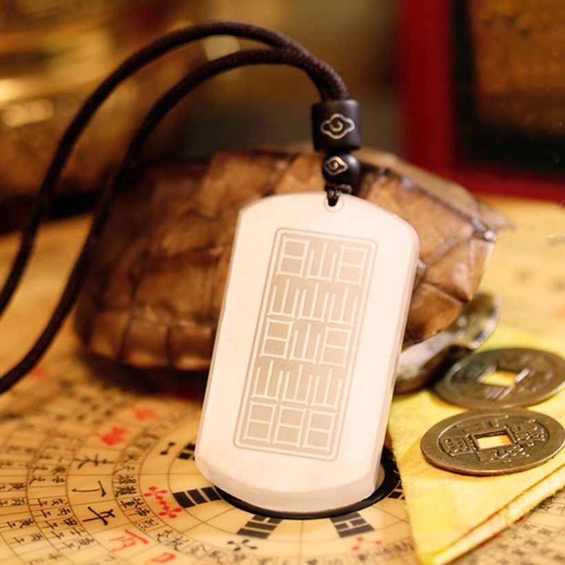 Back of white jade pendant in oblique view displaying flat rectangular reverse side with light milky white jade tone on Feng Shui compass
