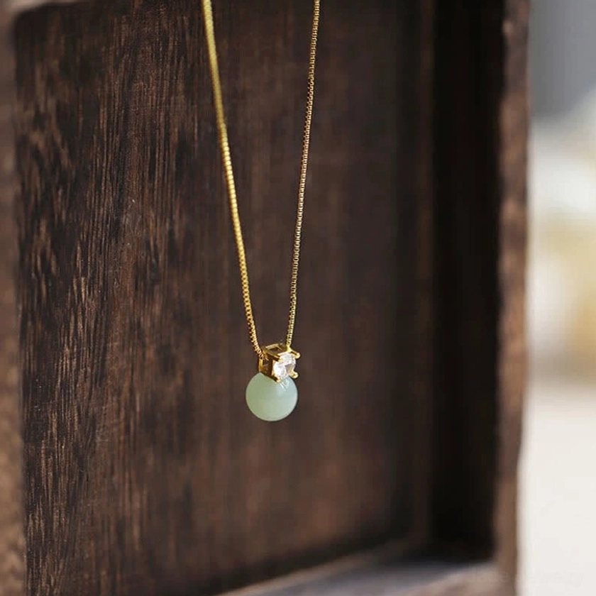Jade bead pendant necklace with zirconia accent displayed in dark wooden luxury gift box, overhead presentation view