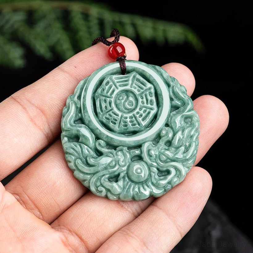 Hand-carved jade dragon yin yang pendant held in palm displaying true size and weight