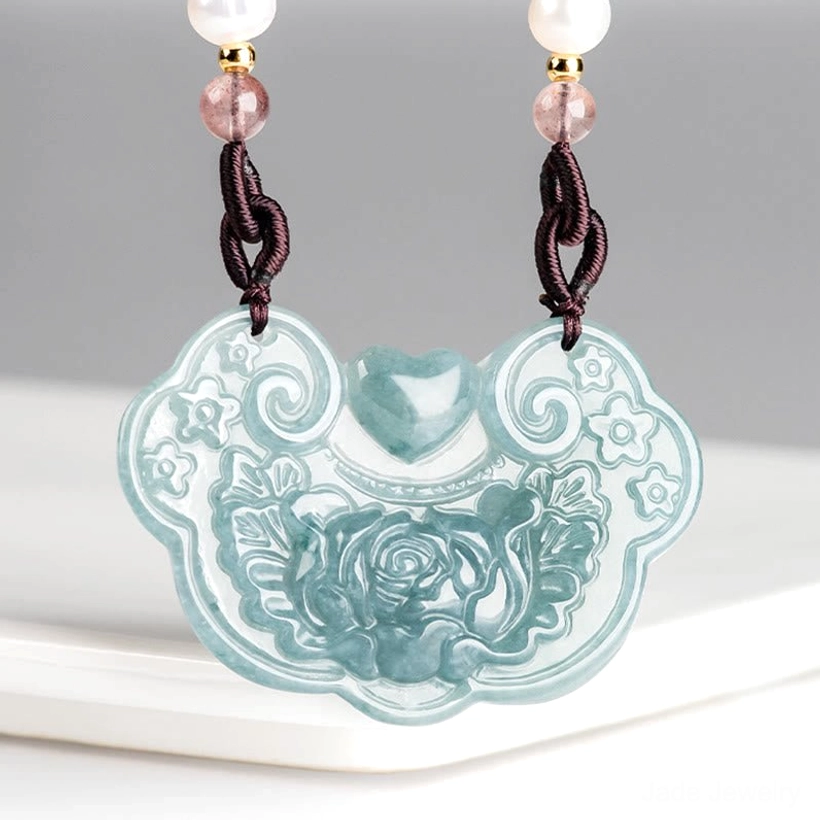 Jade peony lock pendant on white ceramic tray with pink and white bead details, front left angle showing carved prosperity charm