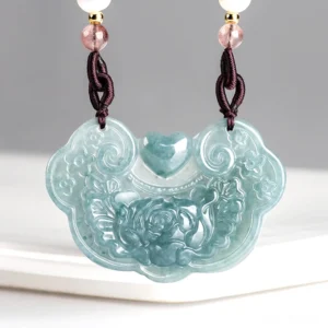 Natural jade peony ruyi lock pendant necklace carved with floral motifs, front view displayed on white ceramic platform, bluish jade prosperity pendant