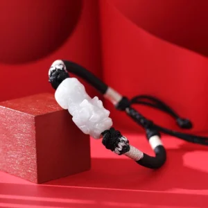 Adjustable jade Pixiu bracelet oblique side view showing pull cord closure and light white carved jade charm detail