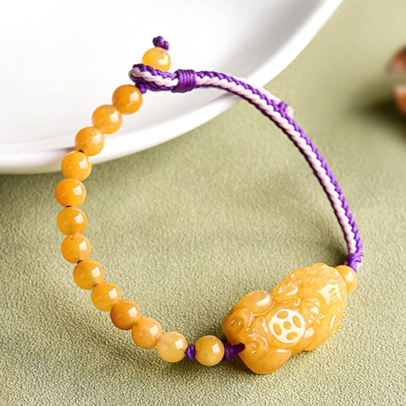 Pi Xiu jade beaded bracelet angled top-down view with carved coin detail on charm