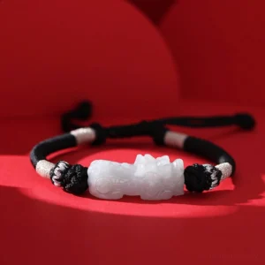 Natural jade Pixiu prosperity bracelet front view with pale carved charm on black braided cord with silver accent knots