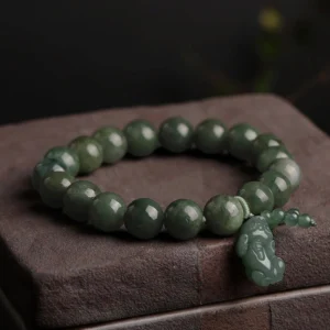 Dark green jade Pi Xiu prosperity bracelet with carved pendant and bead tassel, close-up top view on wooden block