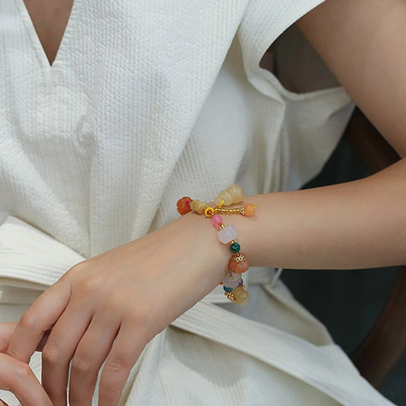Worn golden silk jade pixiu bracelet on left wrist white linen clothing warm toned beads
