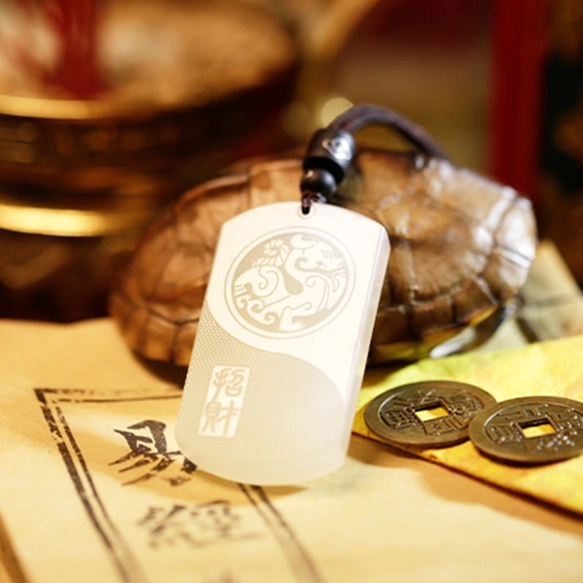 Low front angle view of white jade fortune pendant displaying complete front engraving with vintage copper coins and turtle shell background