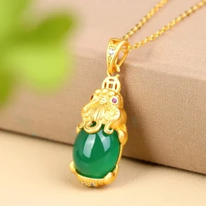 Pixiu jade pendant necklace displayed at three-quarter angle showcasing matte gold charm mount, polished green jade stone, and intricate craftsmanship details with chain