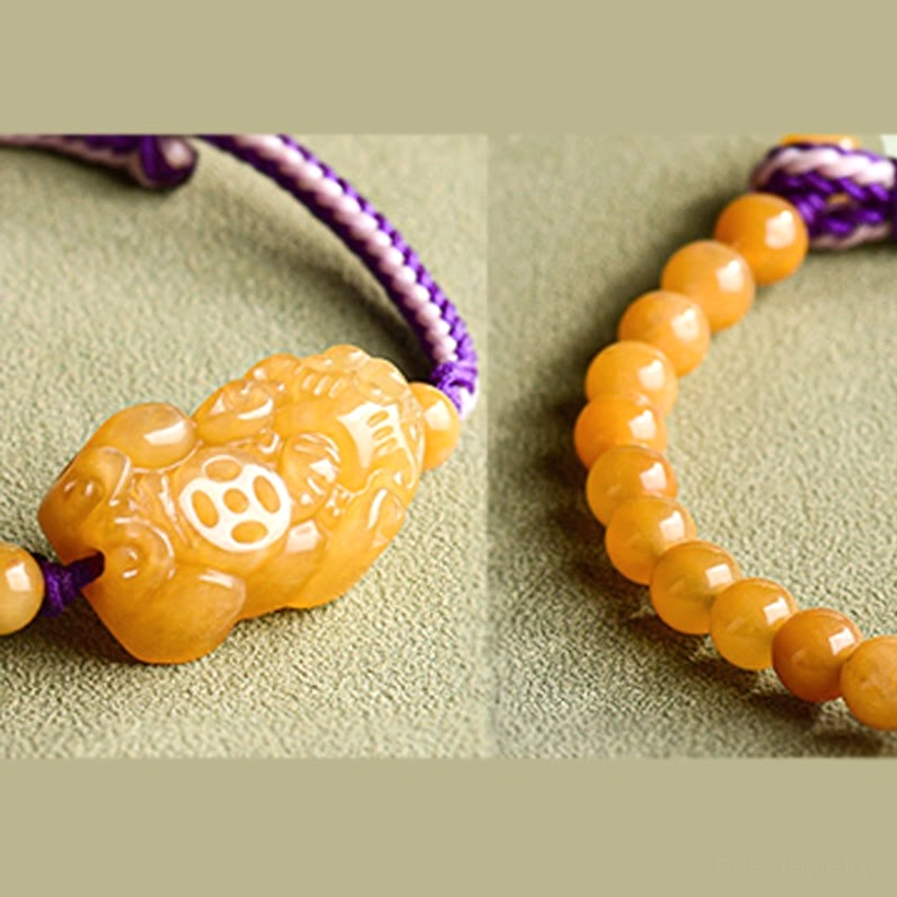 Jade Pi Xiu prosperity bracelet angled display showing yellow round beads and central carved guardian charm