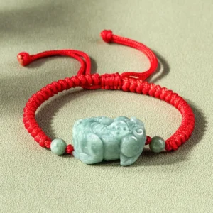 Natural jade Pixiu protection bracelet with red cord overhead flat lay view showing carved jade Pixiu pendant and braided string