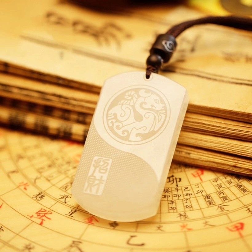 Oblique angle of white jade pendant necklace with light texture and braided dark brown cord on divination compass background