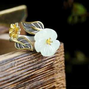 925 silver plated jade plum flower ring close-up elevated shot, displaying gold-accented flower centers and matte silver leaf details