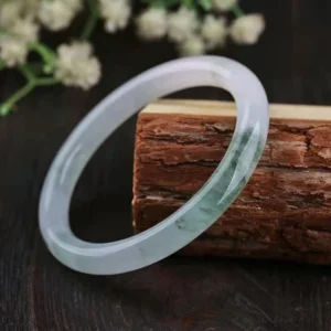 Natural jade bangle bracelet with pale translucent base and green cloud patterns, three-quarter view
