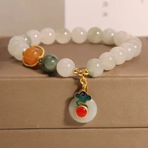 Jade auspicious clouds prosperity bracelet with red agate citrine beads and copper alloy pendant - top-down view on satin display