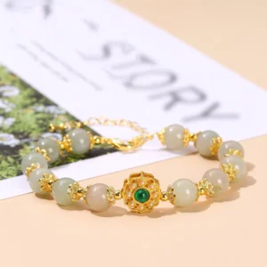Vintage-style jade beaded prosperity bracelet with light brown jade beads and gold copper hardware on magazine and foliage backdrop