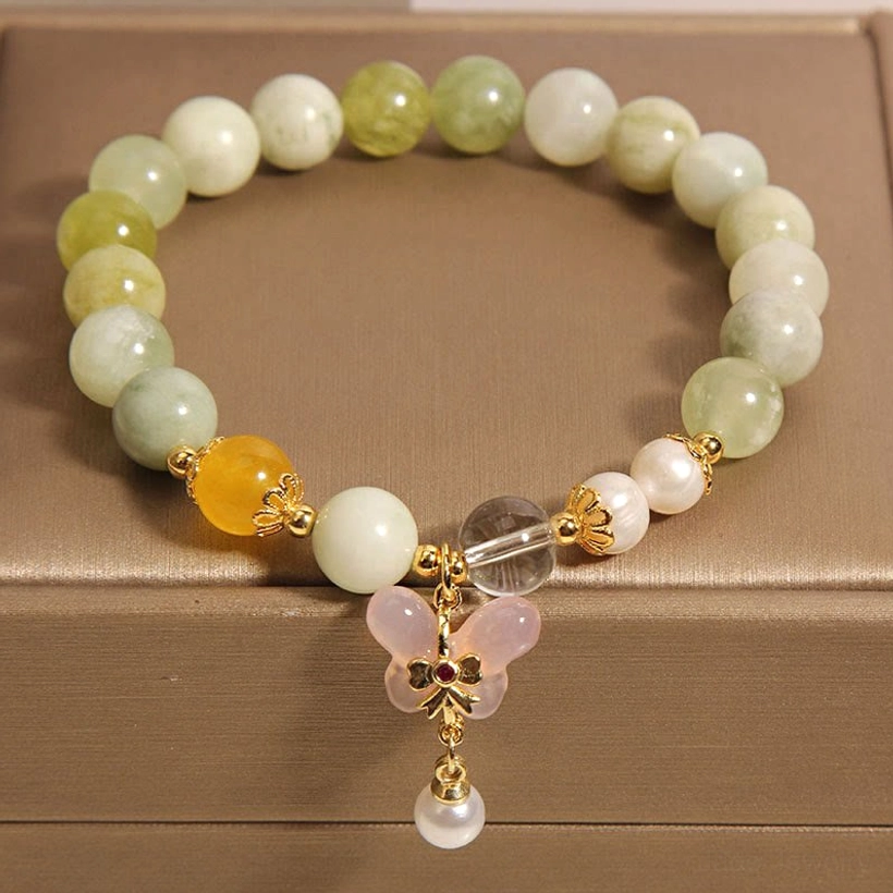 Three-quarter overhead view of jade prosperity bracelet showing bead arrangement and butterfly charm in brown box