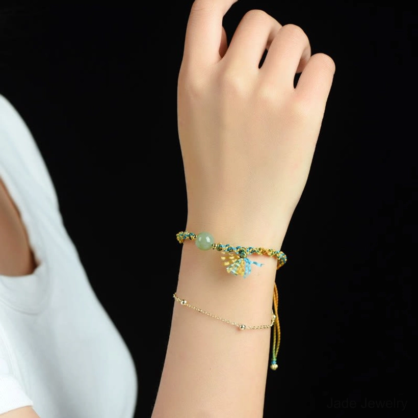 Handmade jade prosperity bracelet worn on wrist with blue yellow braided rope and jade bead