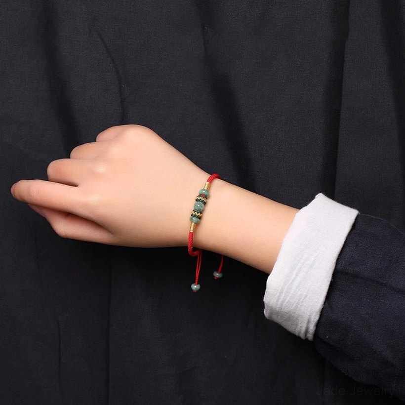 Red jade prosperity bracelet worn on slim wrist with white cuff and dark shirt, showing actual fit and wear
