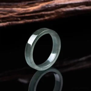 Natural jade prosperity ring left side view - polished grey-green band on reflective black background