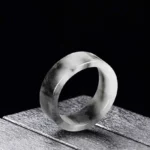 Natural jade prosperity ring with black and white marbled pattern, wide flat band design, side three-quarter view showing smooth polished surface