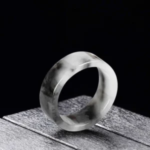Natural jade prosperity ring with black and white marbled pattern, wide flat band design, side three-quarter view showing smooth polished surface
