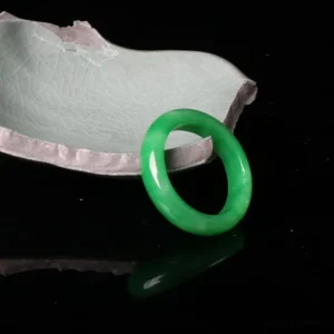 Green jade prosperity ring handcrafted natural stone polished smooth band overhead view black background