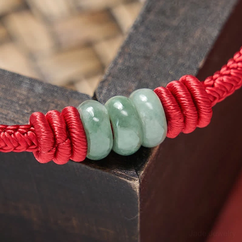 Red string jade protection bracelet detail shot highlighting adjustable sliding knot design and quality jade bead finish