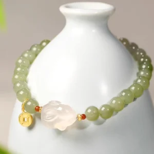 Hetian jade rabbit prosperity bracelet displayed on white ceramic vase showing side profile and bead detail