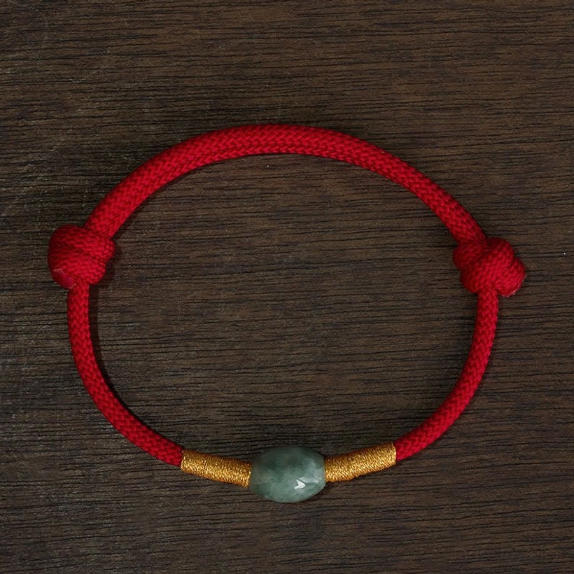 Complete red string jade protection bracelet layout on dark wooden background showing full bracelet design with adjustable cord