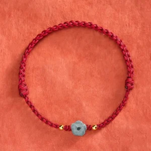 Jade red string bracelet flat lay showing full circular design with adjustable knots and central carved jade charm
